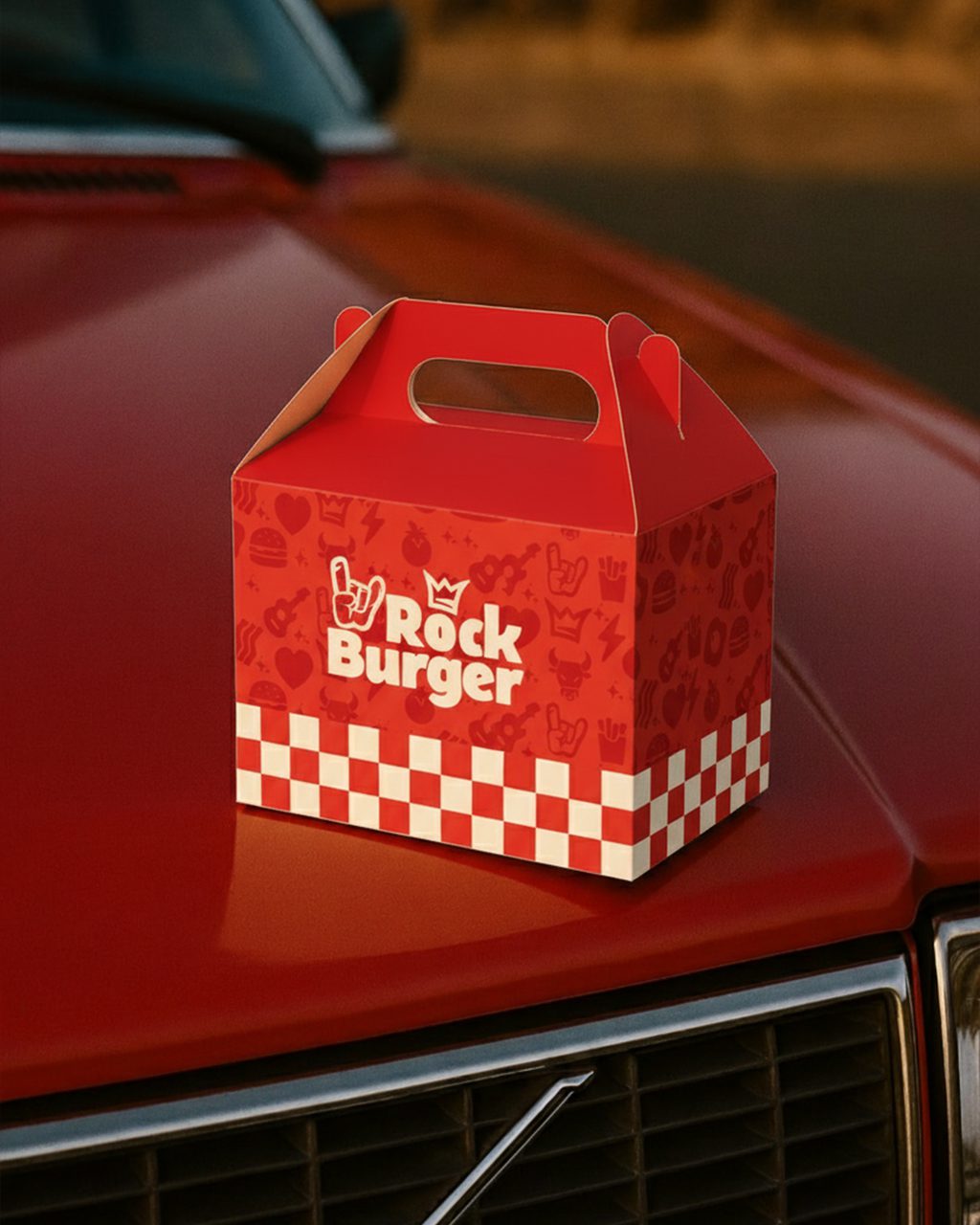A imagem faz parte do projeto de Identidade Visual da Rock Burger e mostra uma representação da caixa de hamburguer sobre um carro vermelho