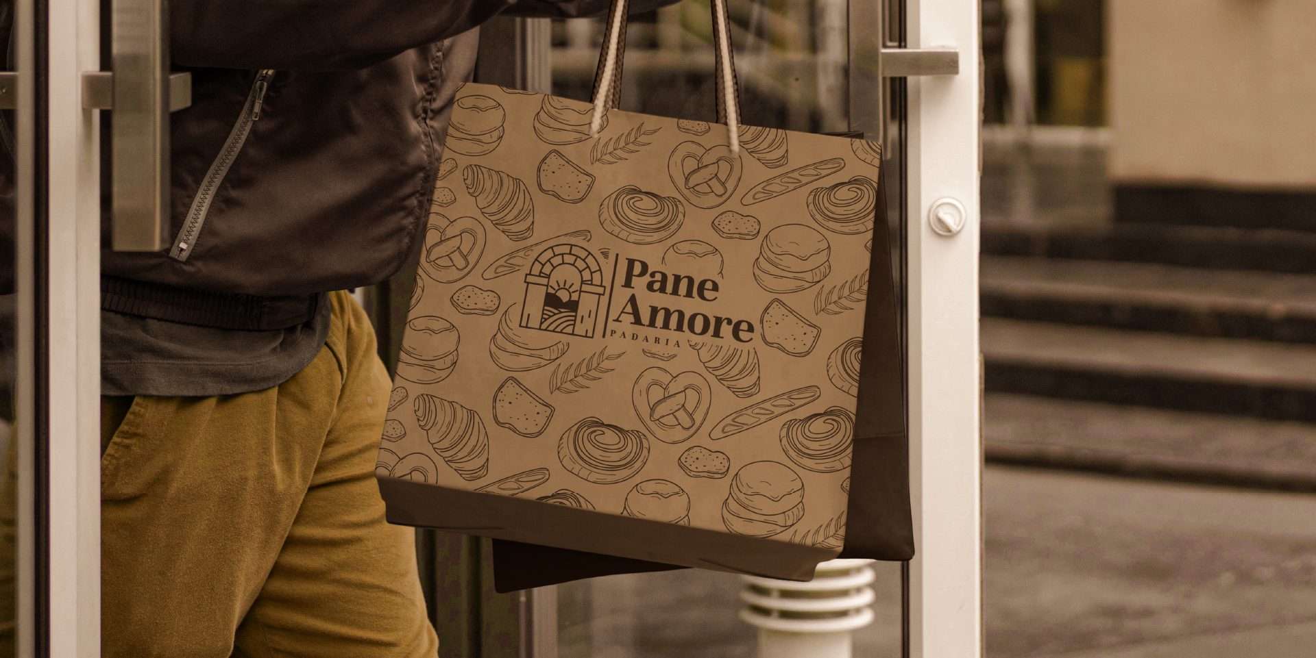 A imagem faz parte do projeto de Identidade Visual da Padaria Pane Amore e mostra uma sacola personalizada com a logo e pattern da marca