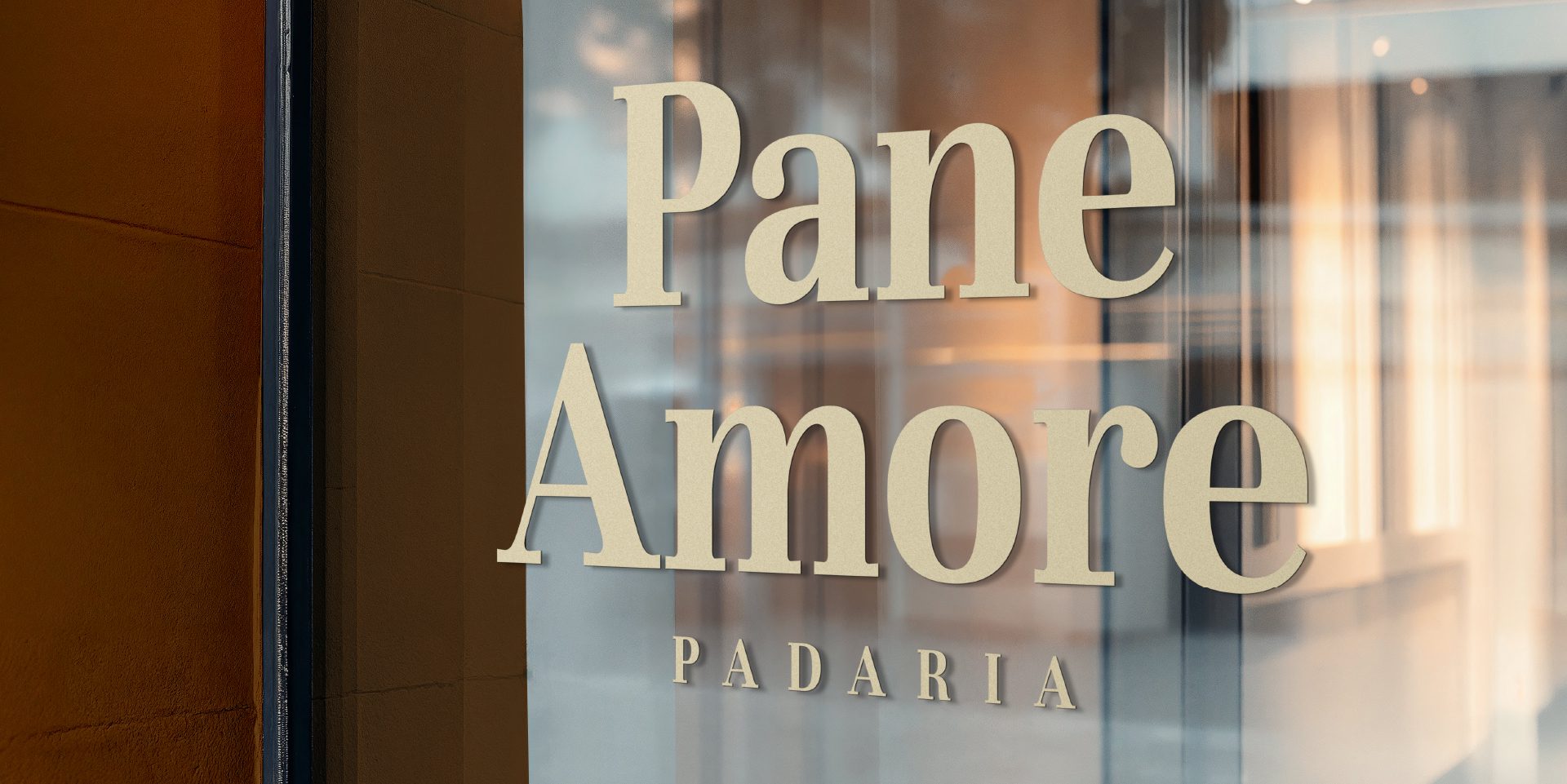 A imagem faz parte do projeto de Identidade Visual da Padaria Pane Amore e mostra o logotipo aplicado a uma vidraça